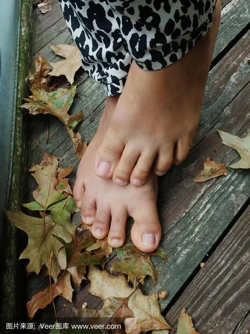 女人光着脚踩在木地板上的树叶上