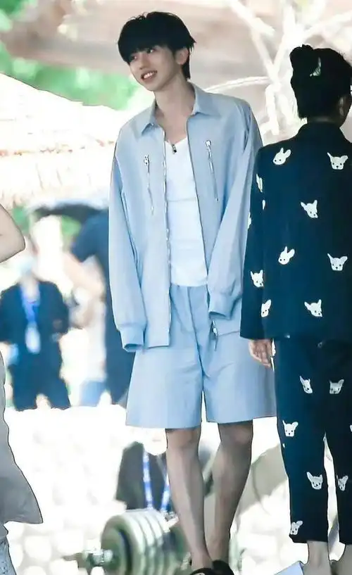 图片中的蔡徐坤身穿一套天蓝色的宽松家居服,配上脚上的黑色拖鞋,显得