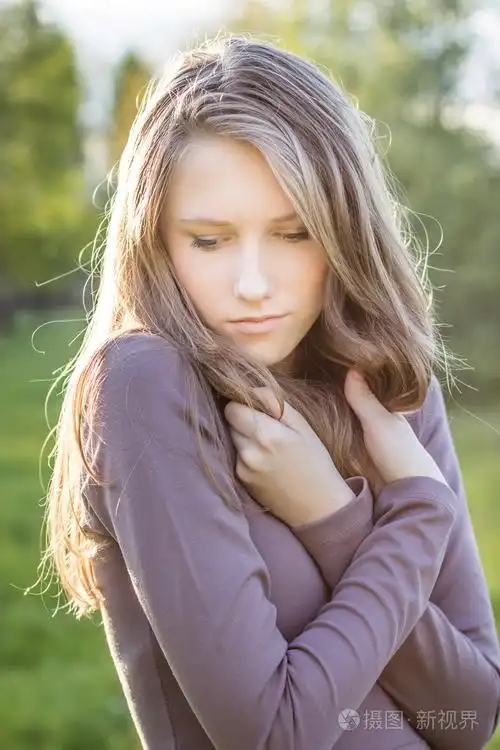 年轻漂亮的伤心女孩低头室外肖像