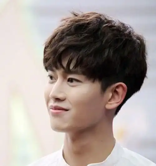 这一款男生烫发发型是好看的齐刘海式的,整个男生蓬松烫发发型虽然有