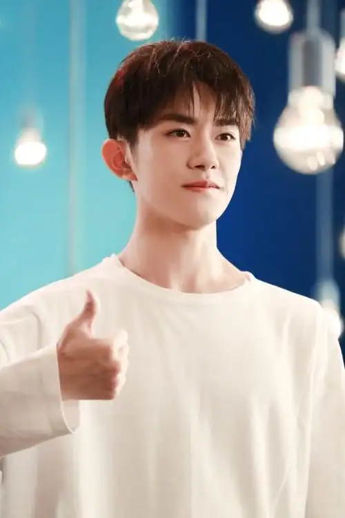 黑裤,眉目清朗神情坚定,在蓝色的背景板中认真表演,单手比赞笑容温柔