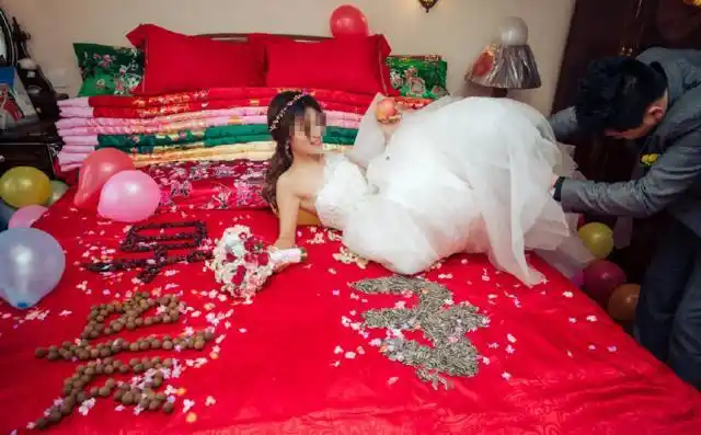 新娘坐在床上,娘家的长辈围着新娘帮她更衣,新娘的衣服从里到外都是