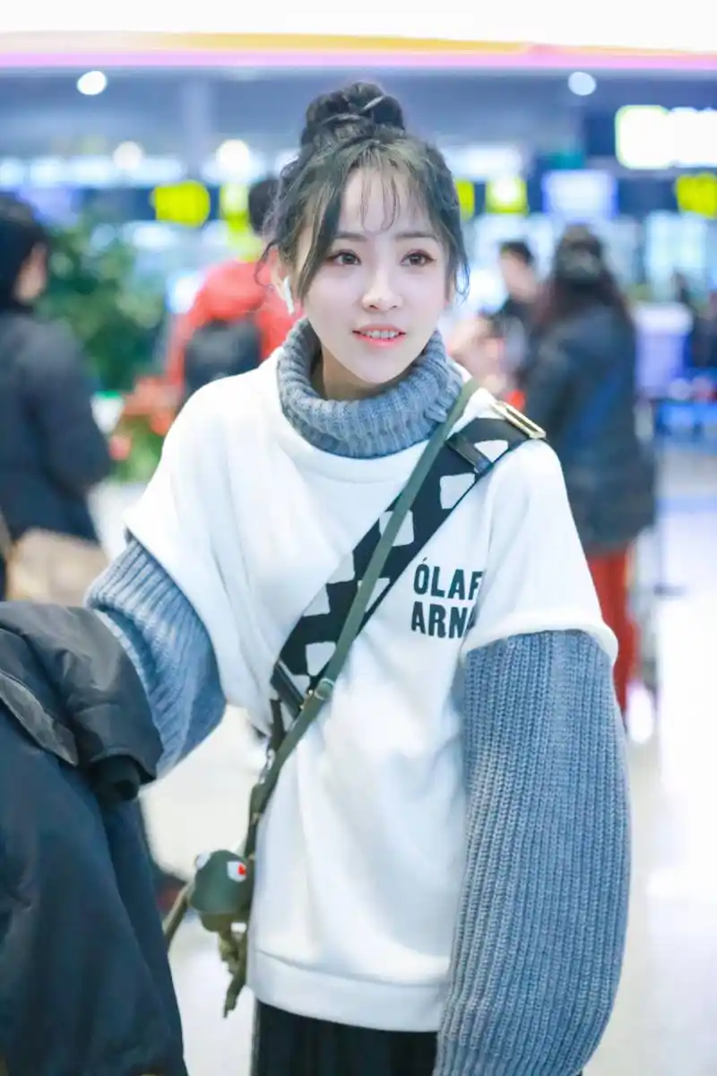 蒋申穿白色短袖卫衣内搭蓝色高领毛衣现身机场,扎丸子头皮肤白皙