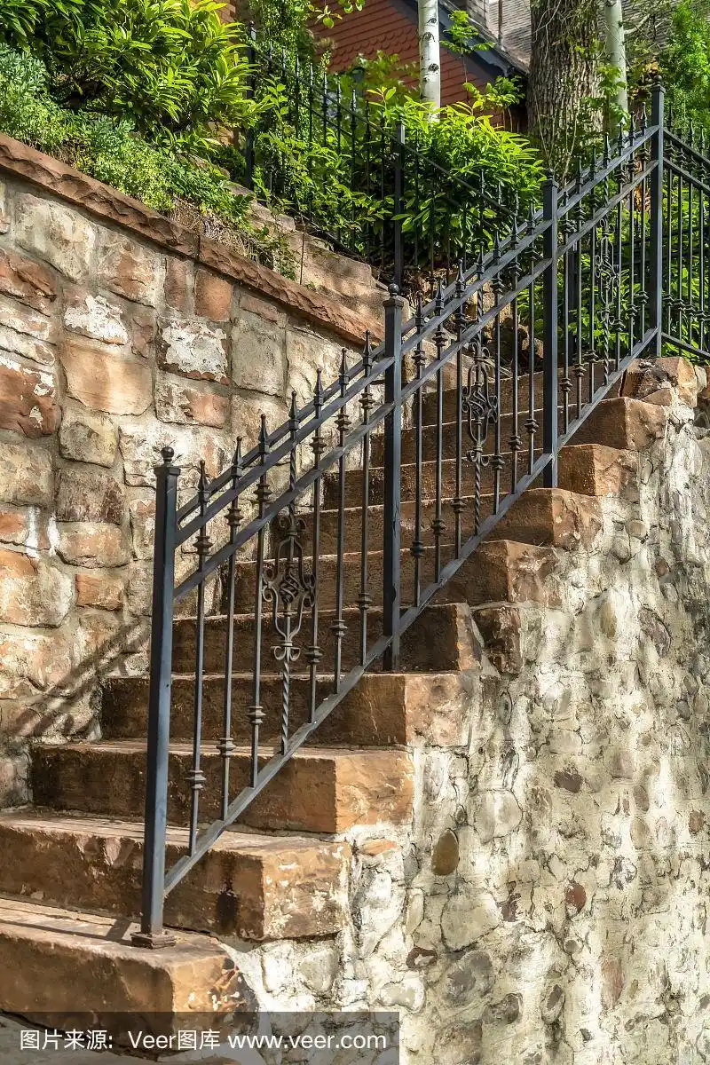 户外楼梯,石阶和黑色金属栏杆对着栅栏