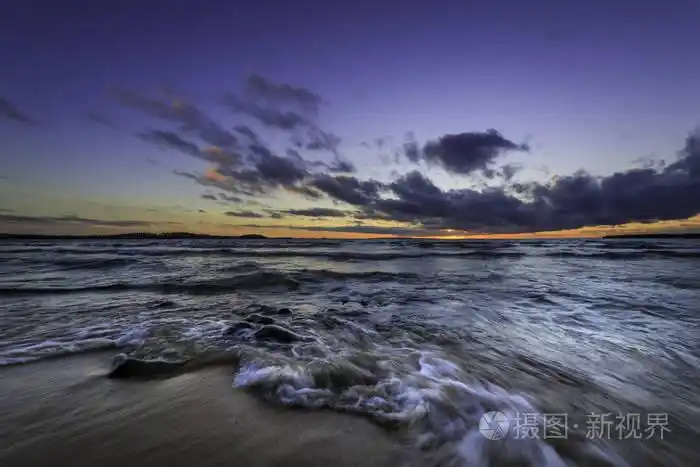 日落时海浪冲向沙滩上