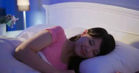 的女人带灯的蓝色沙发枕头早上在家里睡觉的女人晚上睡在床上的女人