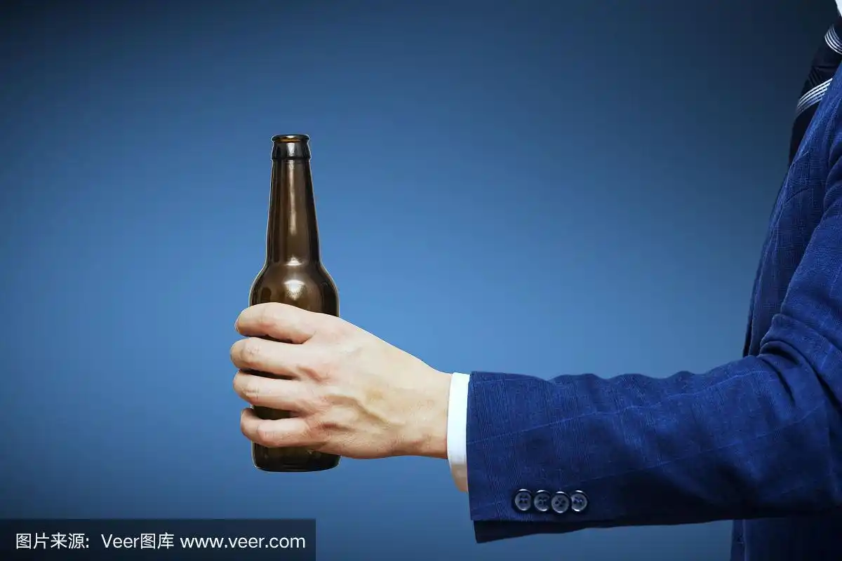 一只手举着一个没有标签的啤酒瓶.