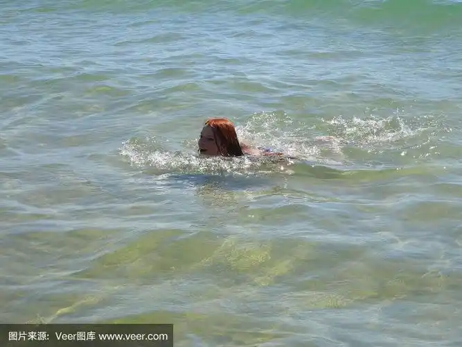 在海边度假的女孩在清澈的大海里游泳的画面