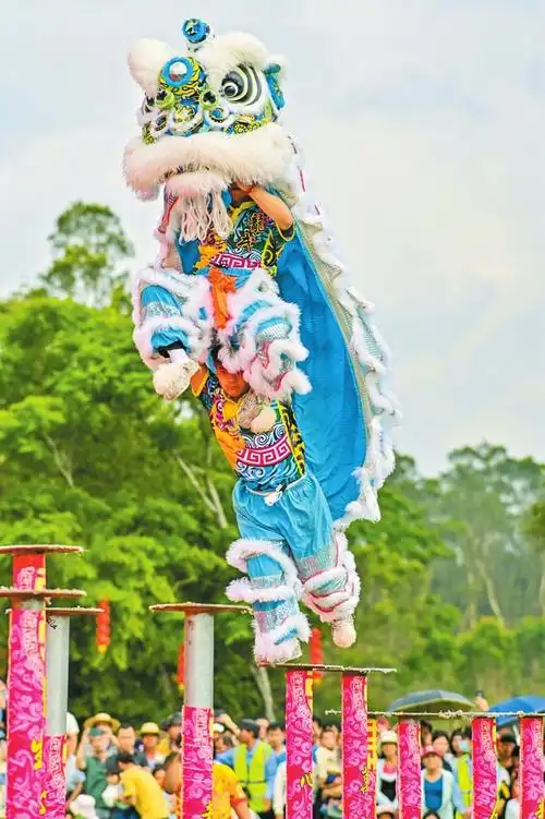 在龙华区新坡镇主会场,游客李琪琪一边观看舞狮表演