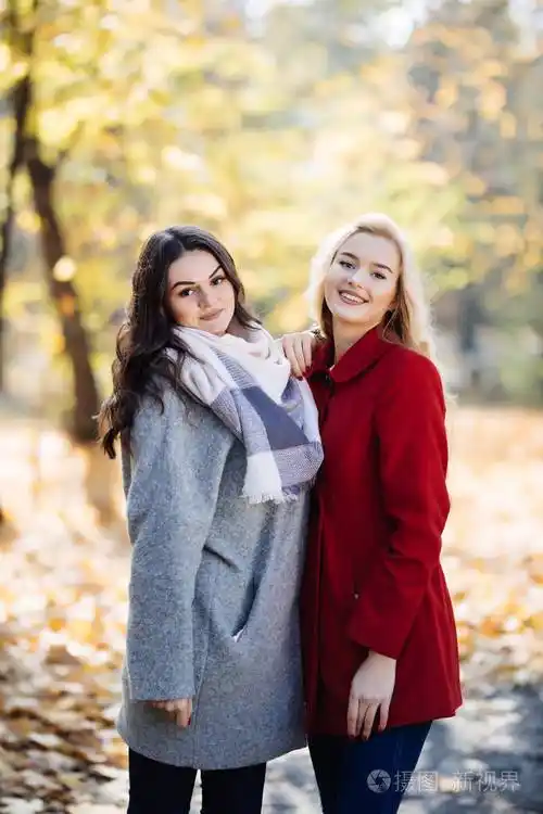 两位年轻女子在秋季公园合影的户外肖像