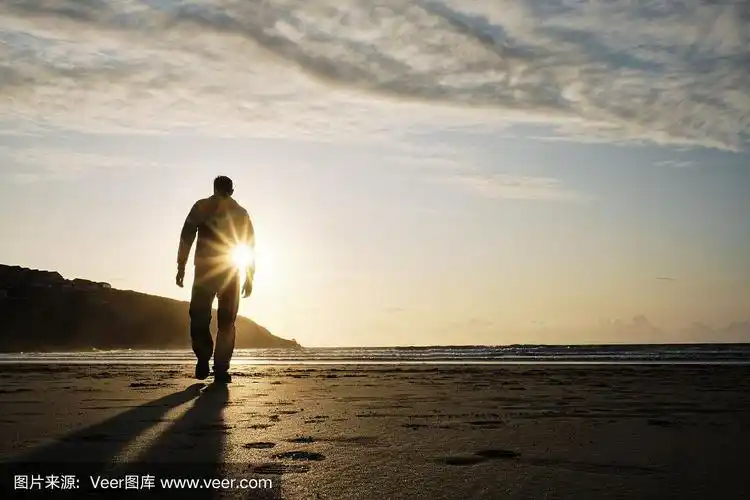 一个背影照亮的人漫步在fistral海滩,纽基,康沃尔在金色的秋天日落