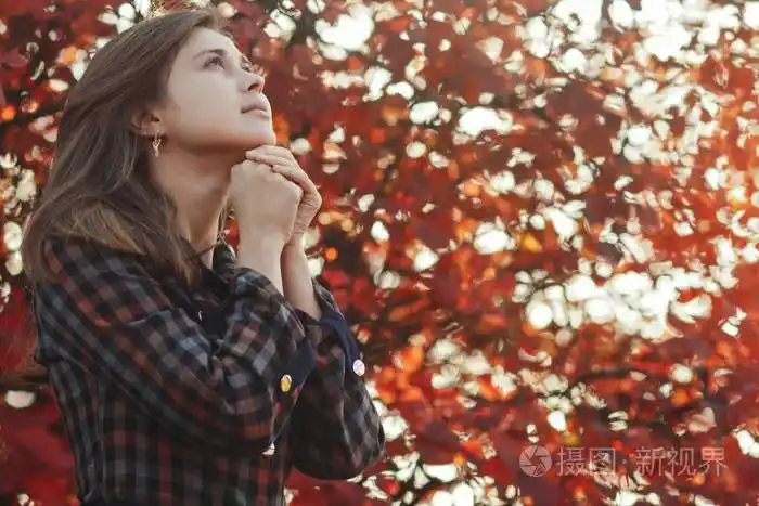 一位年轻女子在大自然中祈祷的画像女孩双手合十在下巴上感谢上帝与