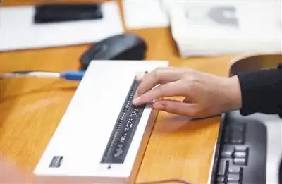 一名工作人员在用盲人专用键盘校对.