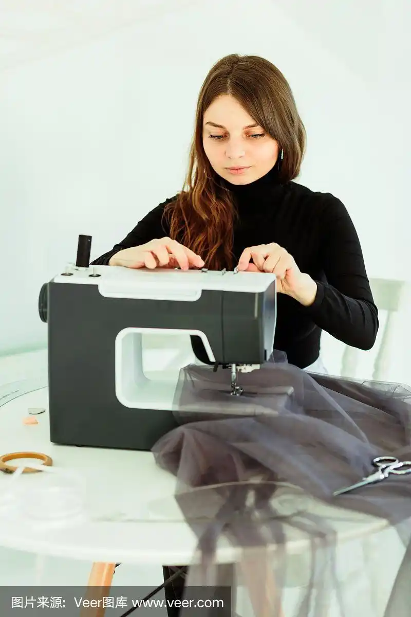 年轻的女裁缝在缝纫机上缝衣服.