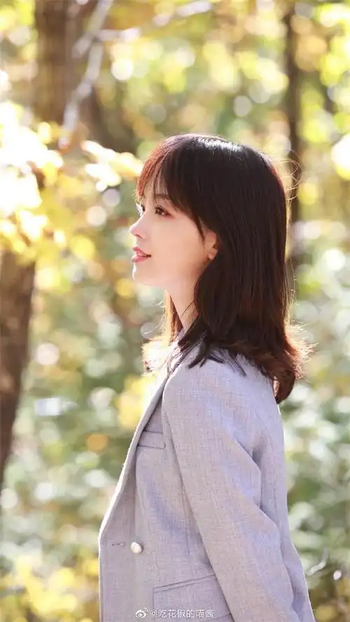 照片中的王冰冰穿着西装外套,独自站在秋日的树林中
