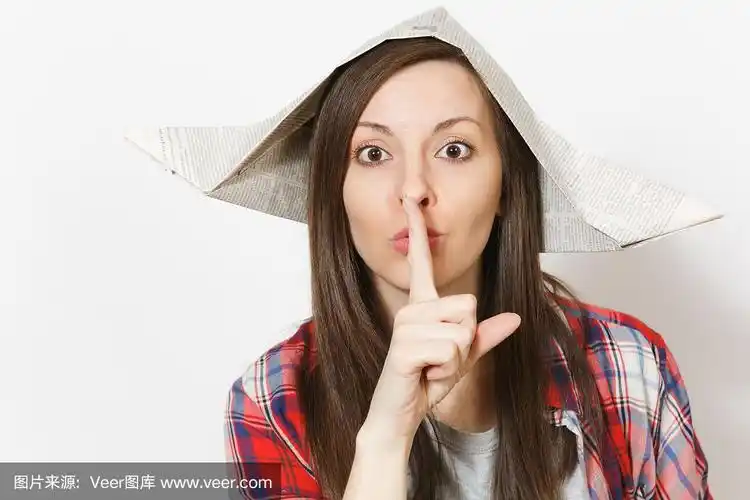 年轻美丽的女人在报纸帽子说嘘嘘安静用手指在嘴唇上的肖像,嘘手势