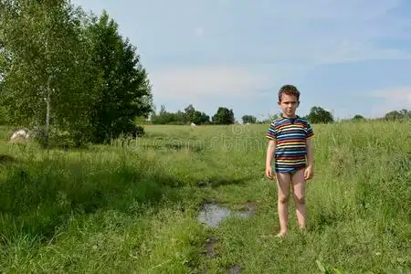 乡下男孩光着脚站在田里的路上.照片