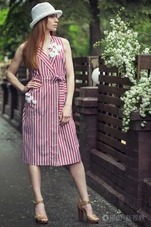 时尚年轻漂亮的女孩穿着休闲服装 (衣服和运动鞋) 雨后走过城市的街道