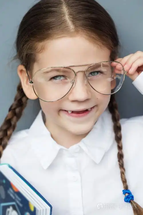 戴眼镜的小快乐女孩.教育, 学校, 学龄前儿童.聪明的孩子与书