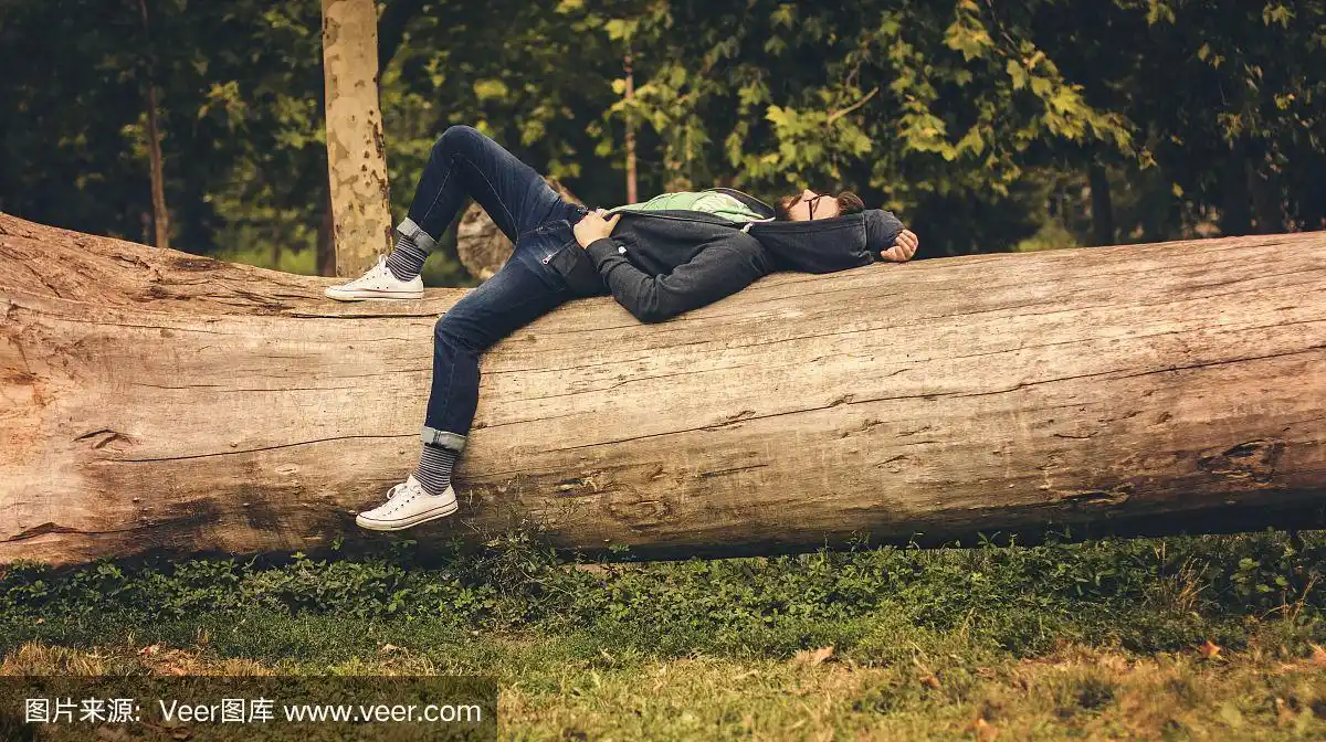 一个孤独的人躺在森林里砍下的树上