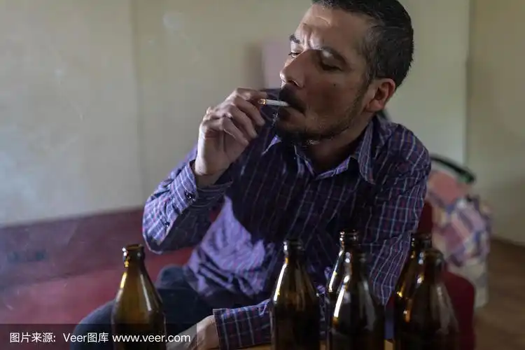 年轻悲伤的醉酒男子喝啤酒和酒精感到浪费,孤独和绝望的痛苦和情绪