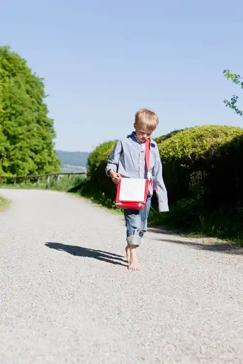 男孩赤脚走在农村公路上
