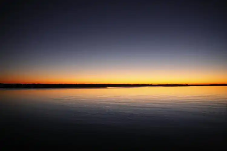 夕阳下蓝天和橙色晴空下平静的海面轮廓