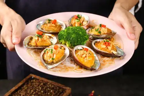 手里端着一盘蒜蓉粉丝蒸鲍鱼