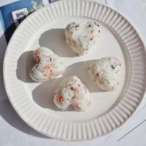 倒入适量的米饭压一下,取出来,保鲜膜去掉,一个心型饭团就制作完成了