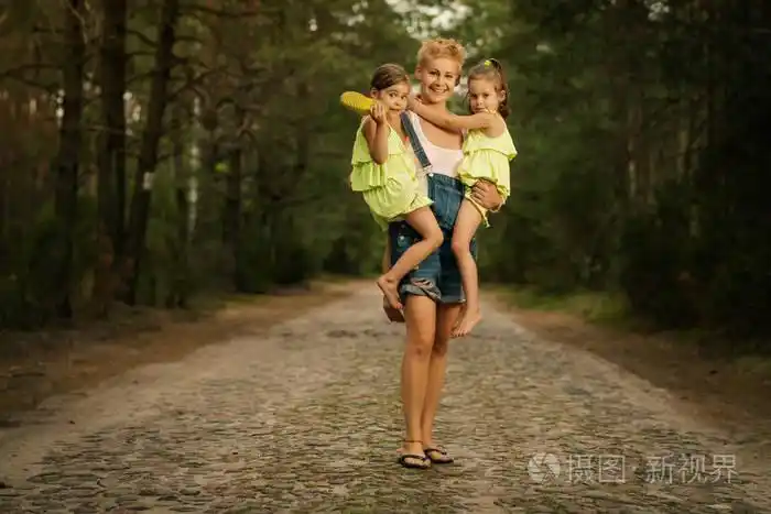 可爱的母亲在树林里抱着两个小女儿