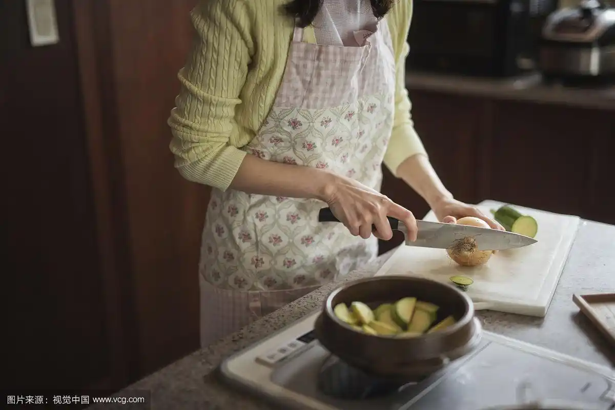 穿着围裙在厨房做饭的女人