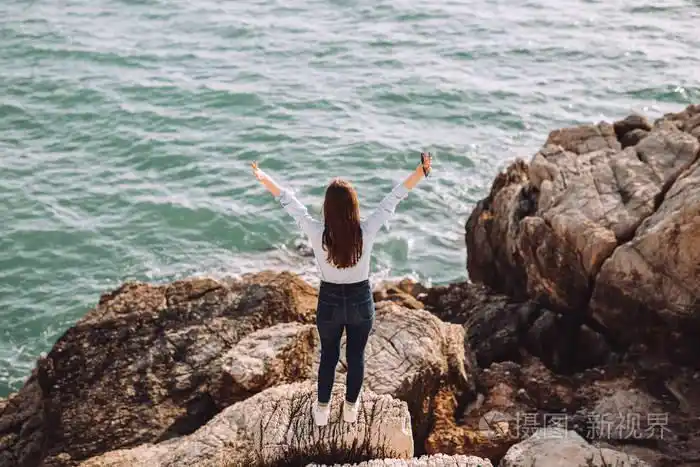 照片 美丽的年轻女孩喜欢住在海边.女孩的脸坐在靠近海边的石头上.