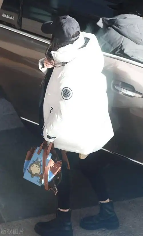 杨幂穿白色长款羽绒服低调现身,头戴黑色棒球帽不失格调