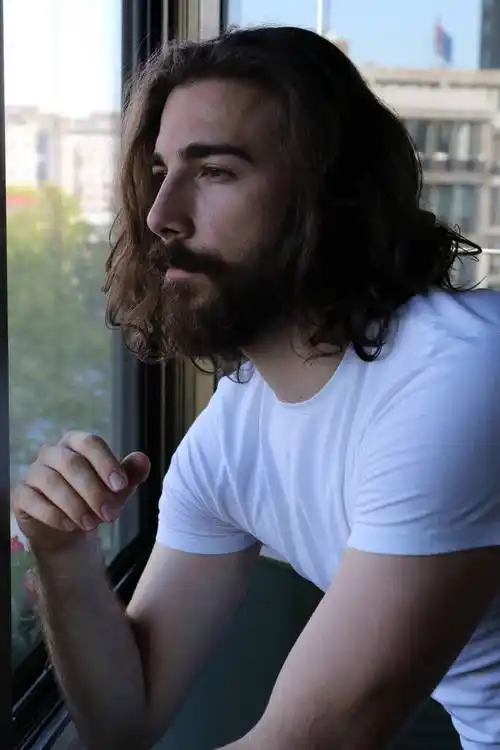 一个留着长发和胡子的时髦年轻的.