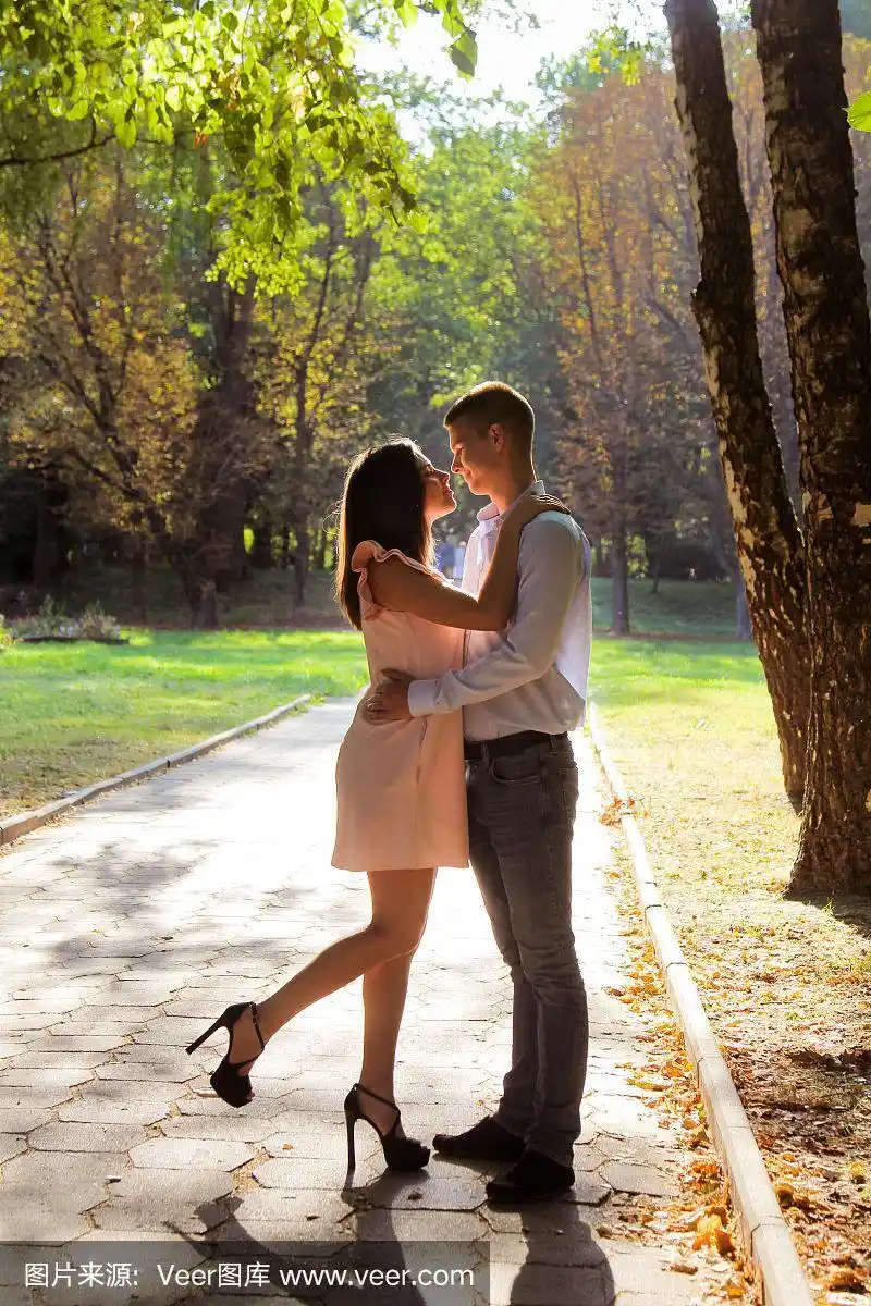 一对在户外相爱的年轻夫妇.互相亲吻和微笑