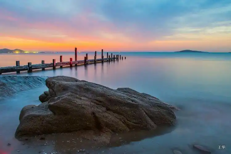 青岛崂山会场海边断桥与美丽的日出朝霞相映成趣