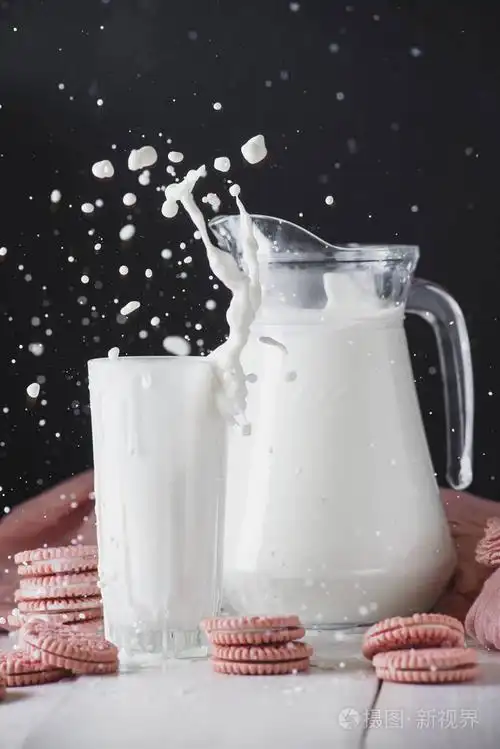 一杯牛奶,一个水壶,一个白色木桌上的美味饼干和一个黑色的背景.