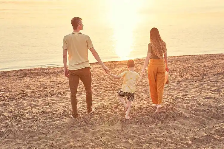 一家三口和他们的儿子躺在前面的野餐毯子上一家人正在海滩上野餐妈妈