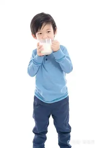 亚洲男孩从白色背景上的一杯喝牛奶