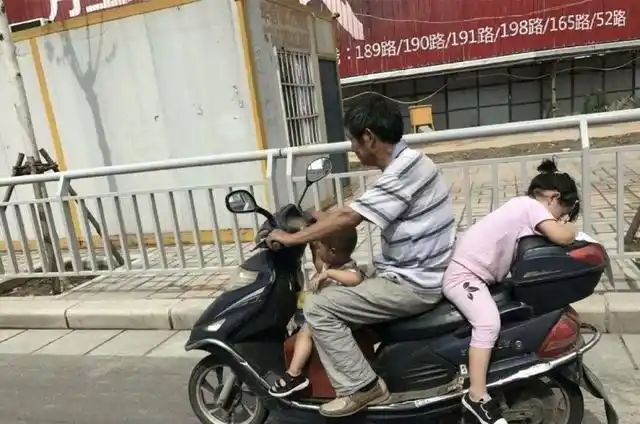 当时,中年男子带着两名孩子,一个小男孩在前面箱子上坐着,一个小女孩