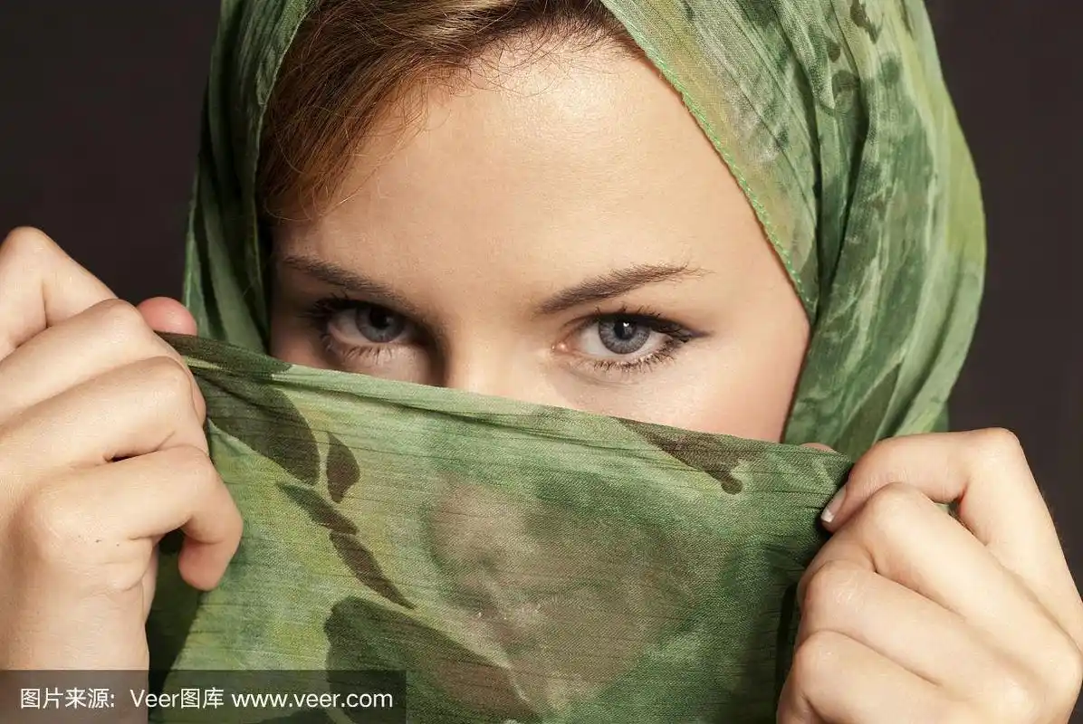 年轻的阿拉伯妇女用面纱显示她的眼睛在黑暗中