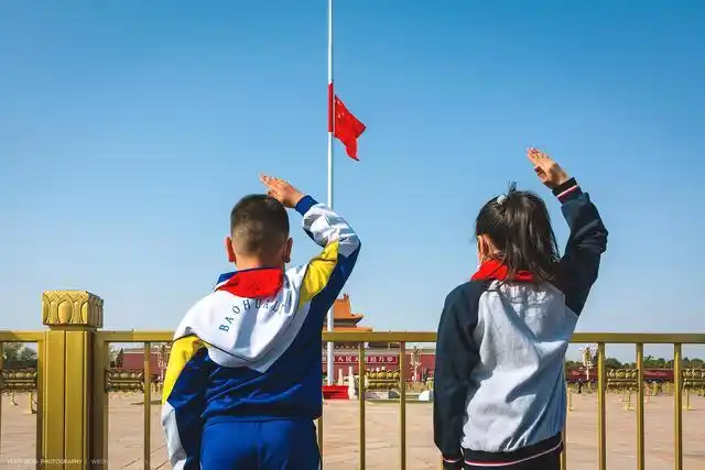 两名少先队员站在护栏下抬起右臂敬少先队礼缅怀英雄,画面干净简洁