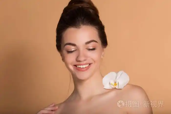 一张年轻漂亮女孩的特写肖像,皮肤完美无瑕,肩上挂着白色兰花.