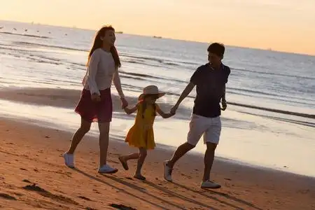 夕阳下一家三口在海边玩耍