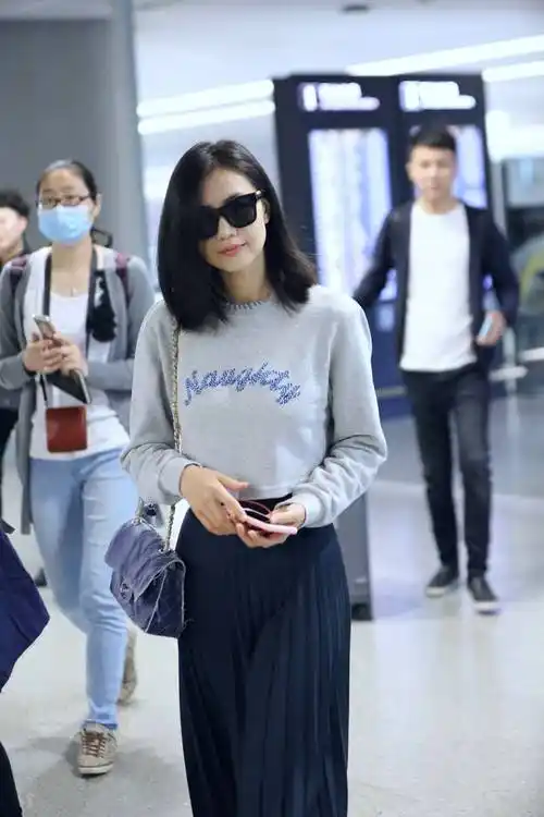 高圆圆走机场妩媚撩发显青春,穿卫衣搭配百褶裙,优雅时尚