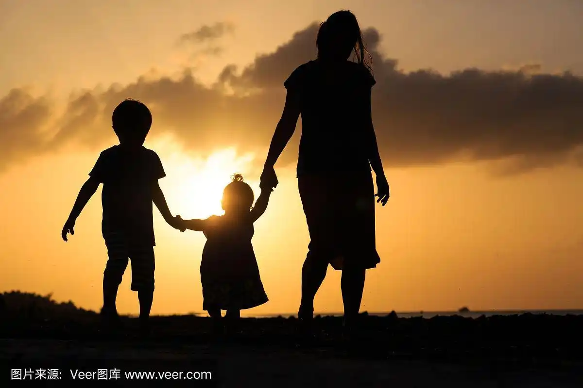 母亲和两个孩子在日落海滩散步