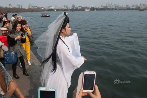 大年初二,杭州西湖边,一位打扮成白娘子造型的游客乘游船上了断桥