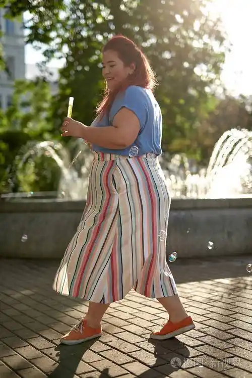 年轻胖女人提着肥皂泡在城市里散步