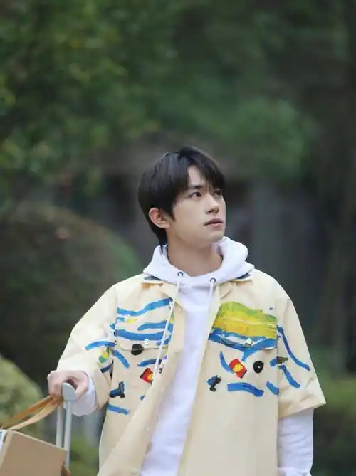 黑色的机动车风衣外套,内搭灰色的卫衣,易烊千玺很喜欢穿卫衣,跟他