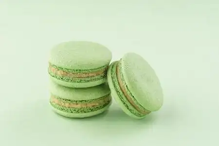 垛关于绿色的阿月浑子树马卡龙向同一的颜色背景照片